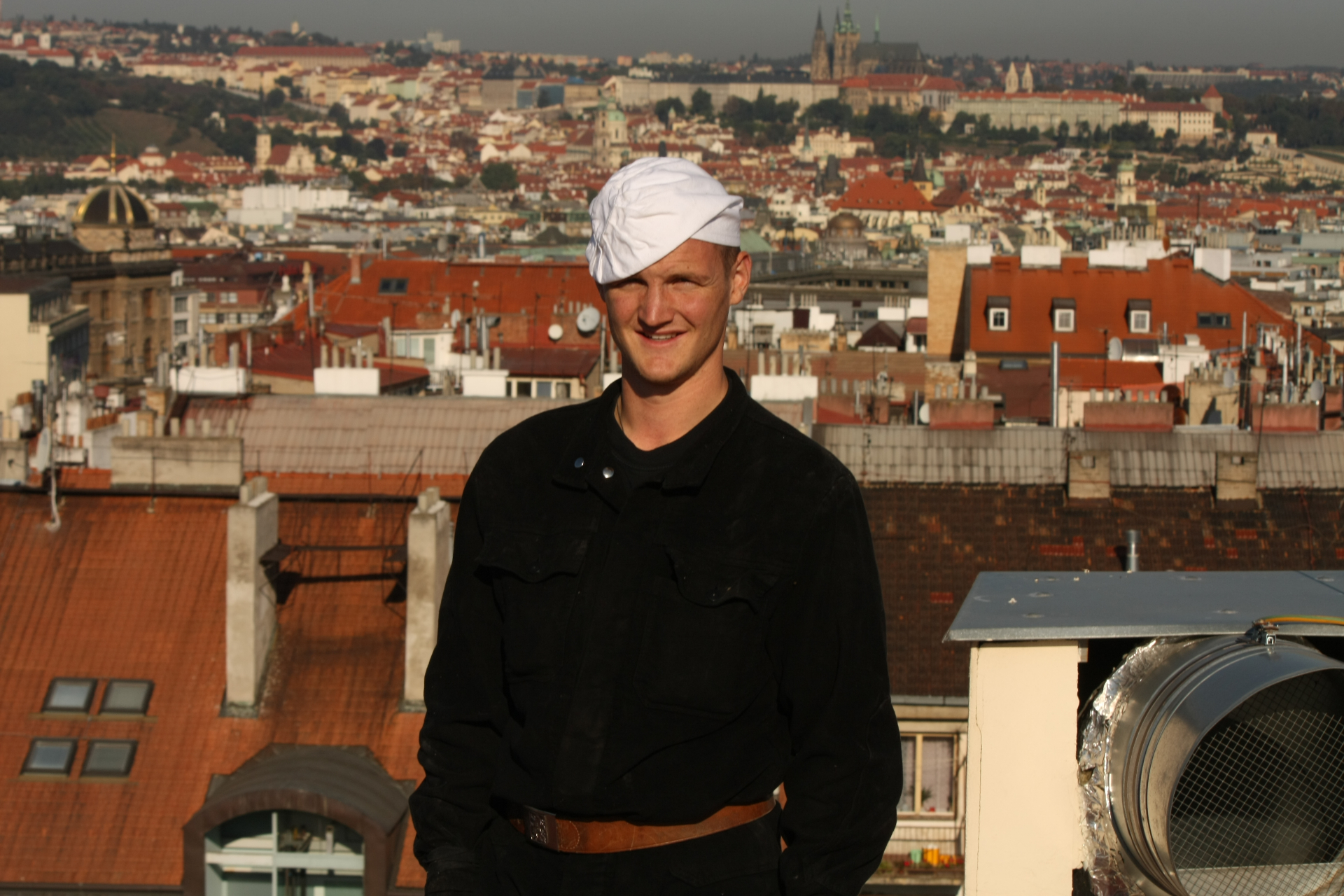 Portrét kominíka Michala Friče s panoramatem Prahy v pozadí